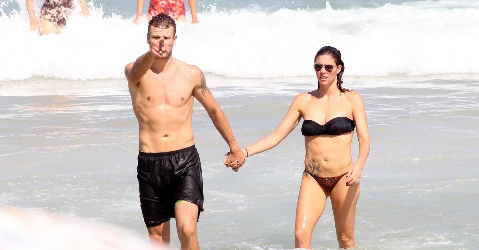 12.abr.2014 -Rodrigo Hilbert aponta para paparazzo enquanto deixa o mar de mãos dadas com Fernanda Lima, na praia do Leblon, no Rio de Janeiro