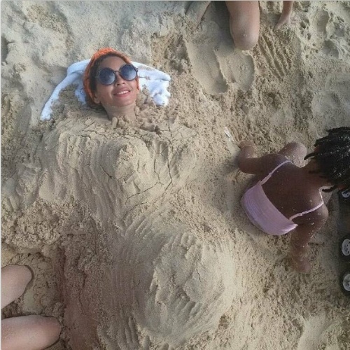 E NÃO LIGA DE SER MÃEZONA - Ficar toda suja de areia da praia, enterrada em um buraco enquanto a filha brinca? Isso não é problema para Beyoncé, que até publicou uma foto da farra em 11 de janeiro, durante viagem de férias com a família