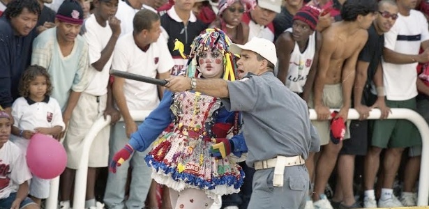 Em imagem do documentário "Geraldinos", PM orienta torcedor fantasiado da personagem Emília durante jogo no Maracaná; ao fundo, torcedores na geral  - Divulgação
