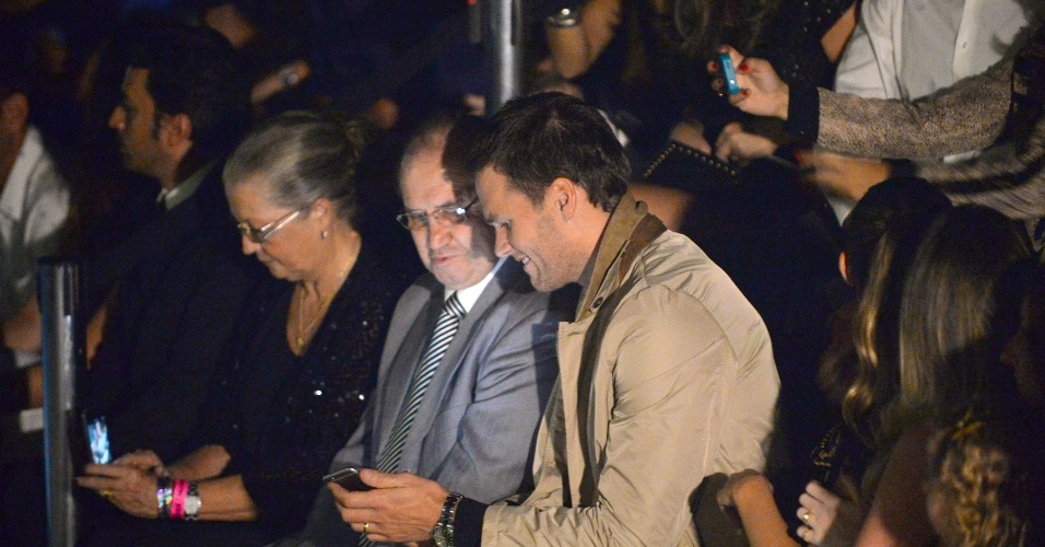 15.abr.2015 - Ao lado de Valdir Bündchen, pai de Gisele Bündchen, o jogador de futebol americano Tom Brady confere o celular durante o defile da Colcci, na SPFW