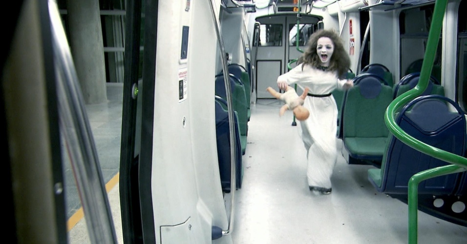Após aterrorizar as pessoas no elevador, Menina Fantasma aparece no metrô, vestida de branco, com megahair no cabelo, maquiagem branca e uma boneca nas mãos assustando as vítimas em um vagão
