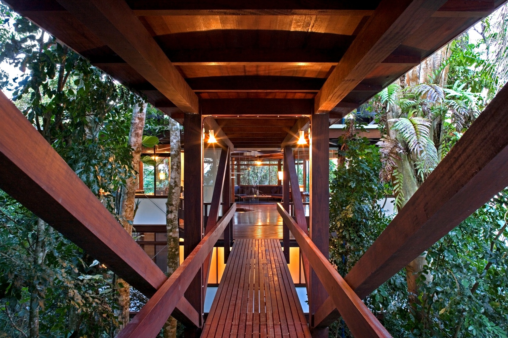 A passarela de ligação do estacionamento com o pavimento social tem piso ripado e cobertura em jatobá, além de apoios e travamentos na mesma madeira. Cercada pela natureza exuberante da Mata Atlântica, a ponte oferece um cenário bucólico à casa Tijucopava, projetada pelo arquiteto Marcos Acayaba - Leonardo Finotti/ UOL