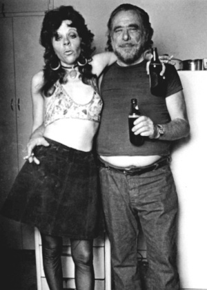 O escritor Charles Bukowski e uma amiga posam para foto, em uma festa em sua casa - Divulgação