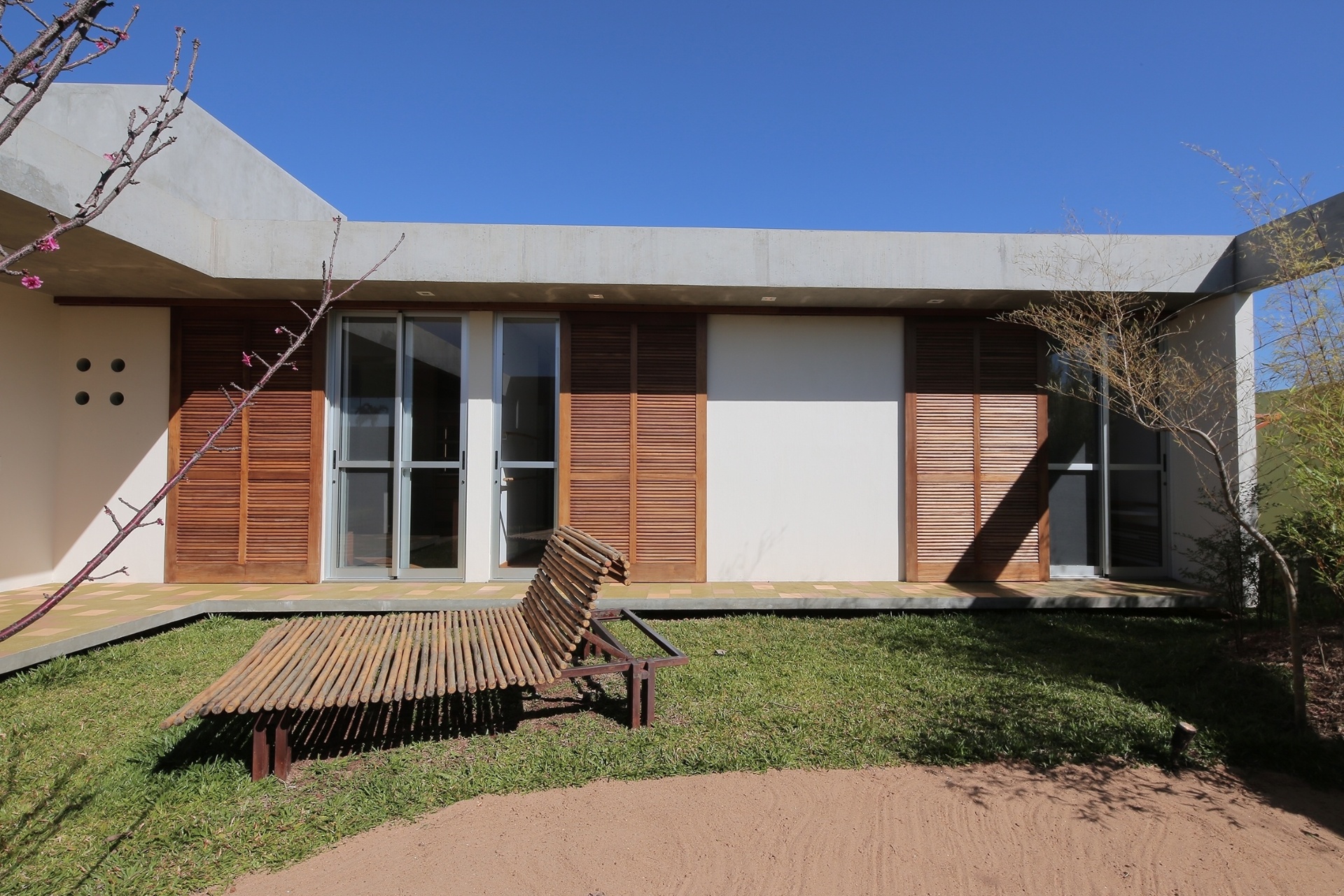 No pátio interno, uma grande viga delimita e contorna toda a casa Madrid, com arquitetura de Monica Drucker, para um condomínio residencial em Marília, interior de São Paulo. Os dormitórios têm portas de correr para o jardim. A cobertura faz o isolamento térmico através das lajes nervuradas protendidas (concreto armado) recheadas com uma camada de isopor de alta densidade. Por cima dela, impermeabilizante (Viapol) e uma camada protetora de concreto com tela, para evitar fissuras - Ruben Otero/ Divulgação