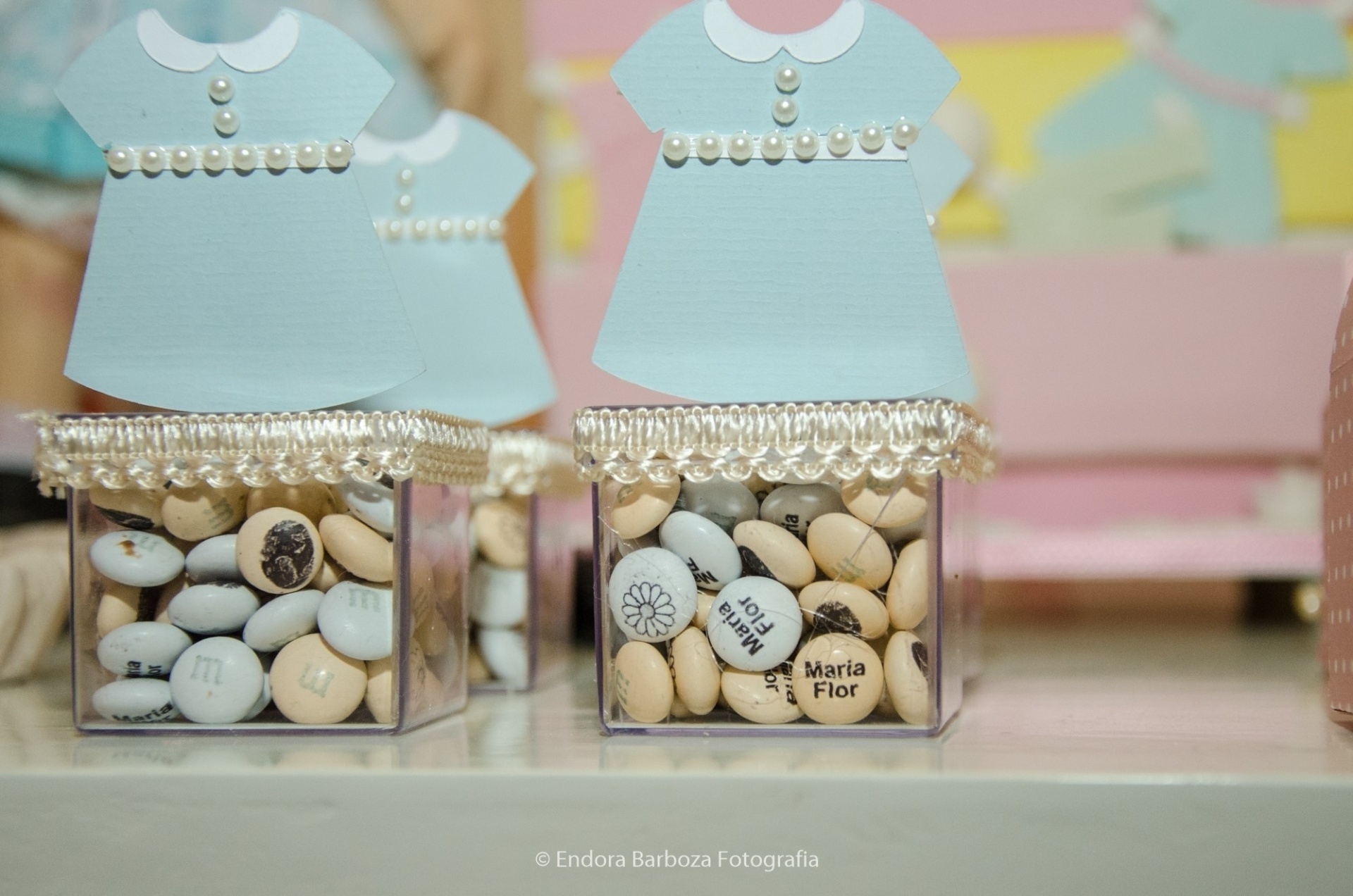 M&M's personalizados foram colocados em caixas que remetiam às roupas das bonequinhas de papel. Os chocolates foram confeccionados nos Estados Unidos e trazidos para o Brasil por intermédio da Enxoval do Bebê nos Estados Unidos (www.personalenxovalbabyshopper.com). A decoração foi assinada pela Fru Fru by Lorena Duque - Endora Barboza Fotografia