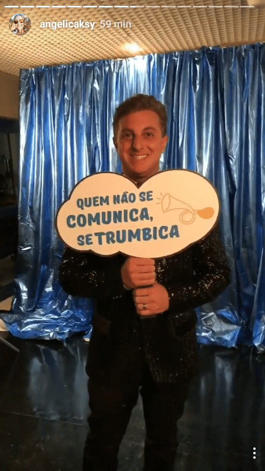 Luciano Huck segura placa com bordão de Chacrinha, "Quem não se comunica se trumbica", nos bastidores do especial "Chacrinha, o Eterno Guerreiro", da Globo e do canal pago Viva - Reprodução/Instagram/angelicaksy