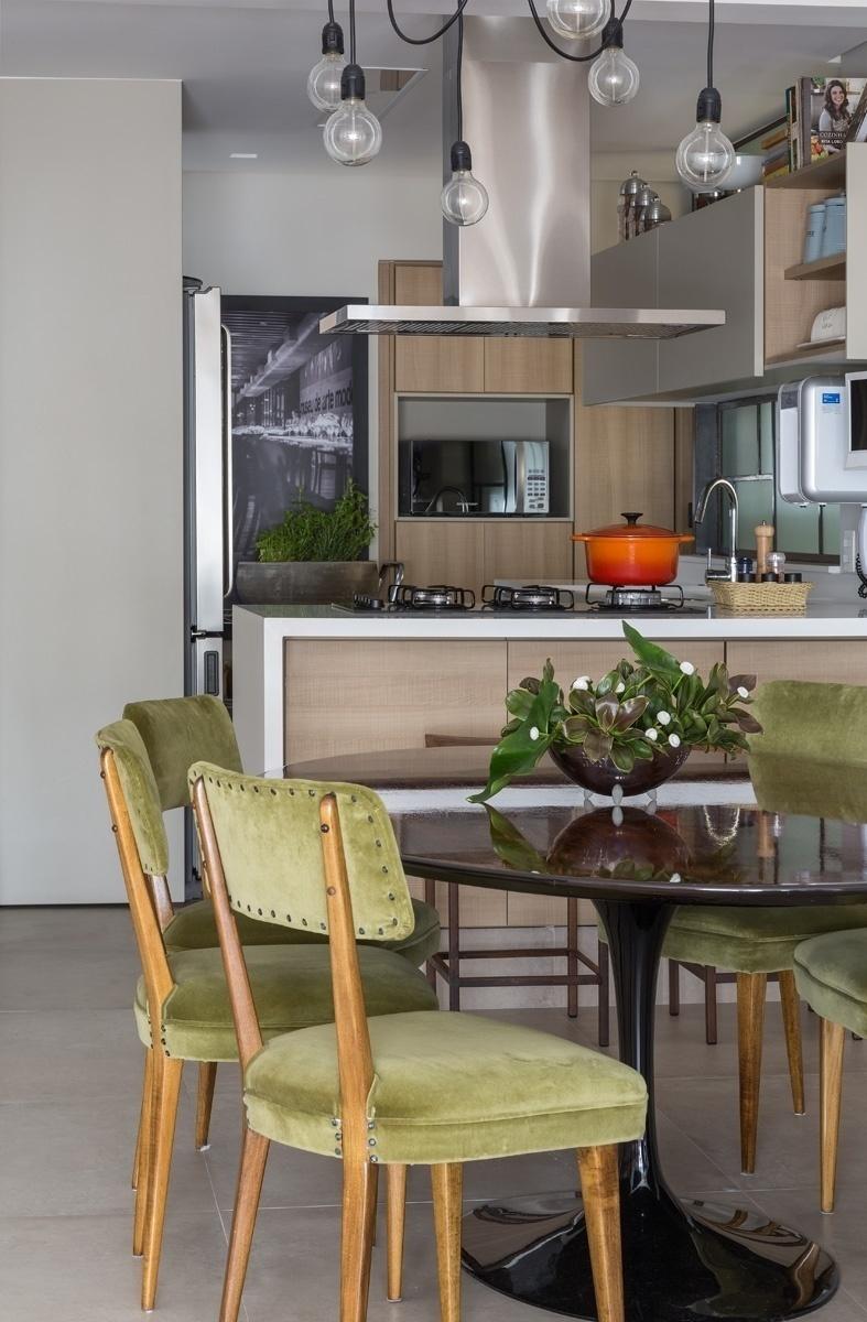 Na sala de jantar, a arquiteta imprimiu uma atmosfera industrial com toques de modernidade. Ela aproveitou a nobre mesa Saarinen com tampo de jacarandá, comprada num garimpo pela moradora, e mesclou com cadeiras vindas de um antiquário. Os estofados das cadeiras foram renovadas com um elegante veludo verde - Evelyn Müller/Divulgação