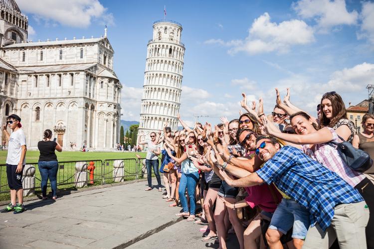 Turistas se divertindo com a inclinação da Torre de Pisa, na Itália