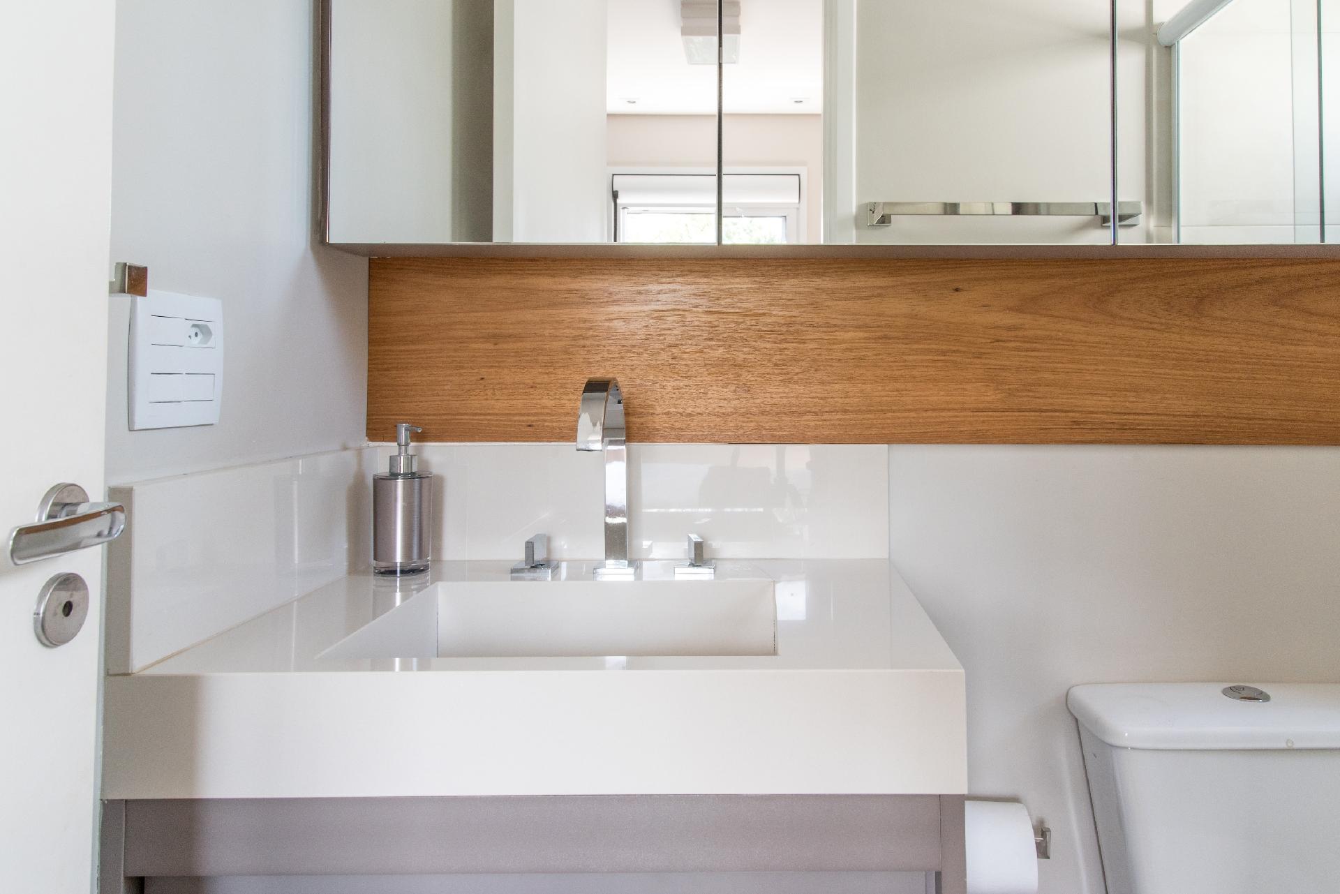 Pequena e sob medida, a cuba integrada à bancada foi providencial, pois não atrapalhada a abertura da porta neste projeto da Spaço Interior. Todos os acabamentos são claros, devidamente aquecidos pela faixa de madeira que traz um toque especial ao banheiro de 2,60 m² - Julia Herman | Divulgação