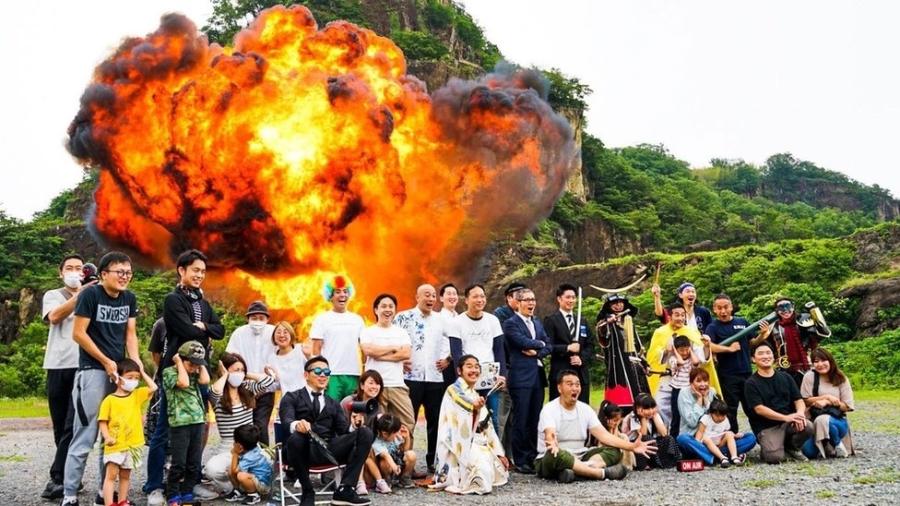 Os turistas posam para fotos enquanto grandes e pequenas explosões acontecem ao fundo  - Cortesia