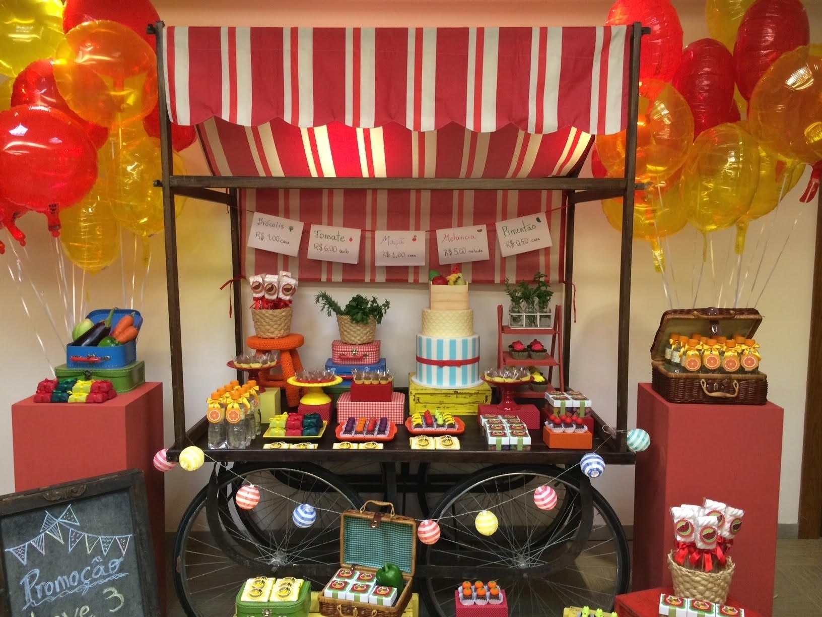 Na festa com tema feira livre, assinada pela empresa Decorando Emoções (www.decorandoemocoes.com.br), a mesa do bolo era a reprodução de uma barraca (um tampo de madeira retangular apoiado sobre estrutura de rodas). Dois pilares laterais também serviam como suporte para os docinhos - Divulgação