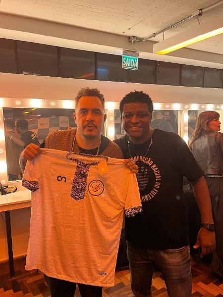 Marcelo Carvalho, em seu trabalho contra o racismo no futebol, entrega camisa para o rapper Marcelo D2
