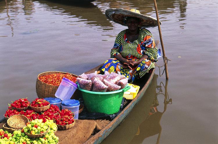Mulher vende mercadorias em canoas em Ganvié, a maior vila flutuante da África