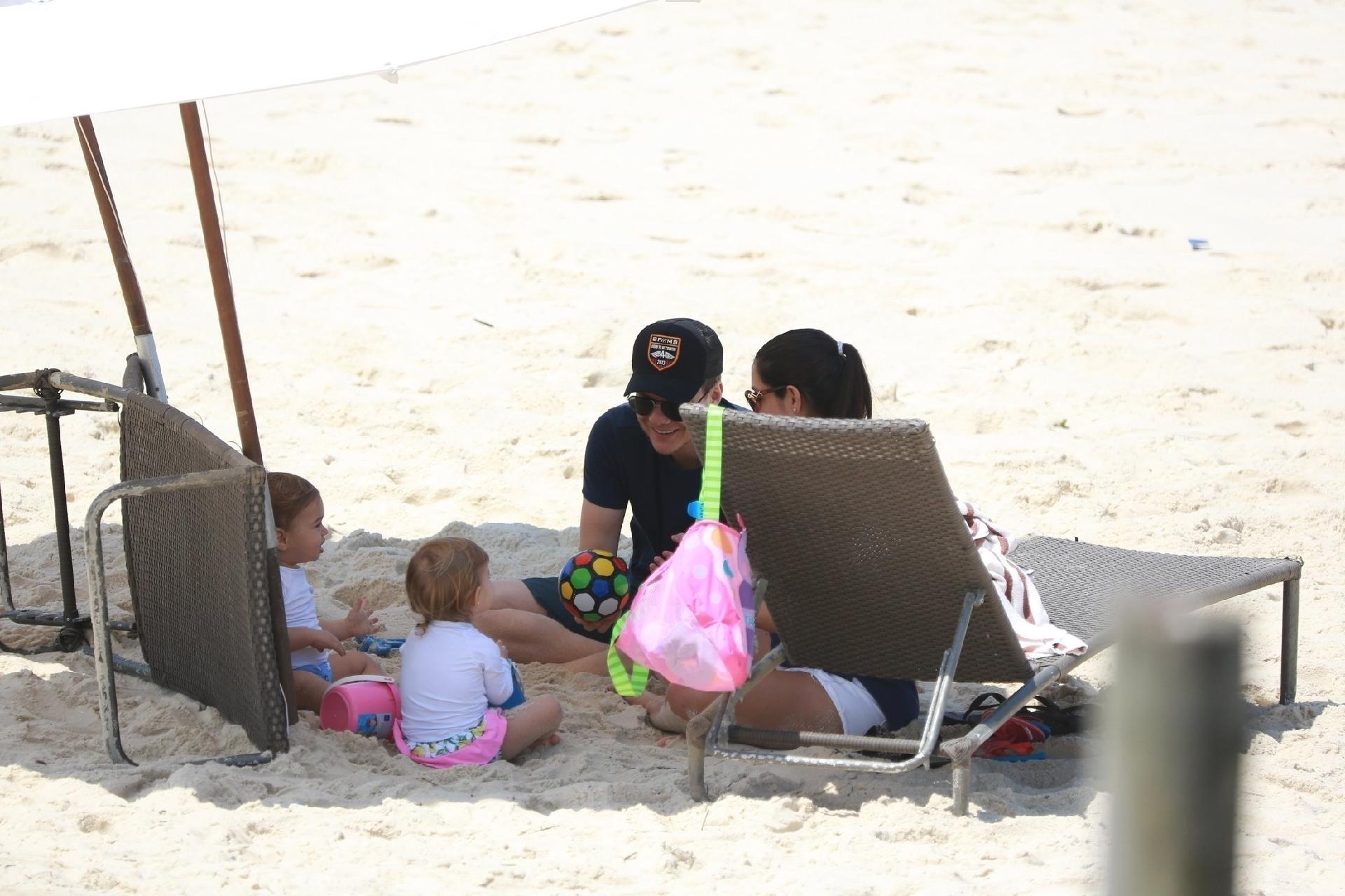 Durante o passeio, que durou duas horas em frente ao hotel em que a família está hospedada na Barra da Tijuca, Michel Teló e Thais brincaram de bola com Melinda e Teodoro na areia - AgNews