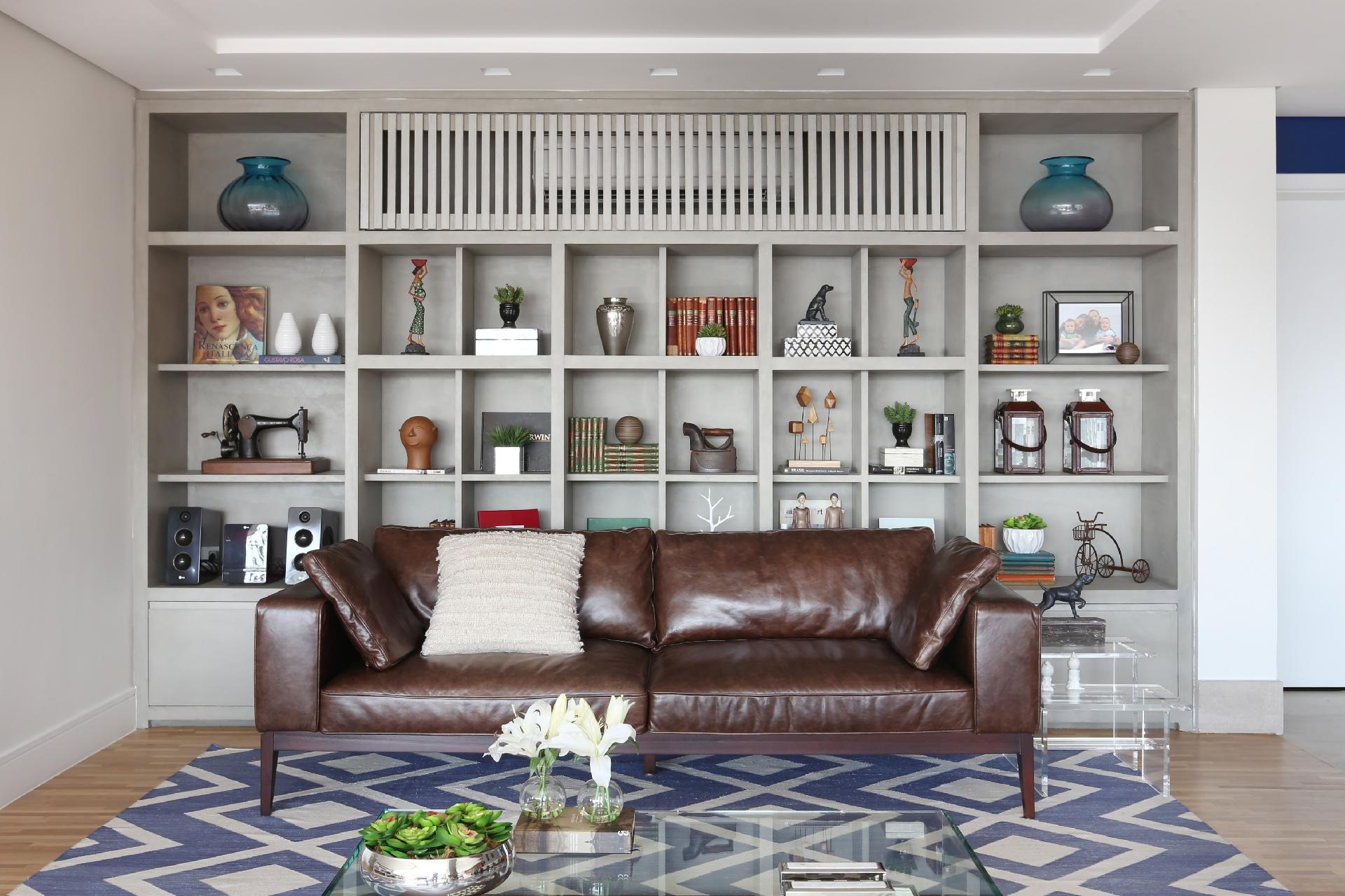 Alocar o ar-condicionado na sala é sempre um desafio, pois o aparelho tende a sobrecarregar o visual da decoração. Neste living, o problema foi resolvido pelas arquitetas da Triarq, que bolaram um nicho na estante para ocultá-lo. As ripas não podem ser muito fechadas para não interromper a passagem de ar - Mariana Orsi | Divulgação