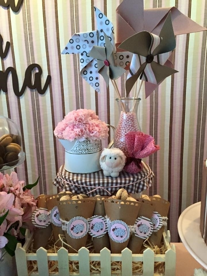 No cercado de madeira, cones de papel kraft cheios de bombons de biscoito wafer. Atrás, sobre o banquinho com assento forrado em tecido xadrez, a ovelhinha de pelúcia lembrava o tema deste chá de fraldas. Cataventos de tecido e regador  branco com cravos naturais deram um ar vintage a esta decoração - Divulgação