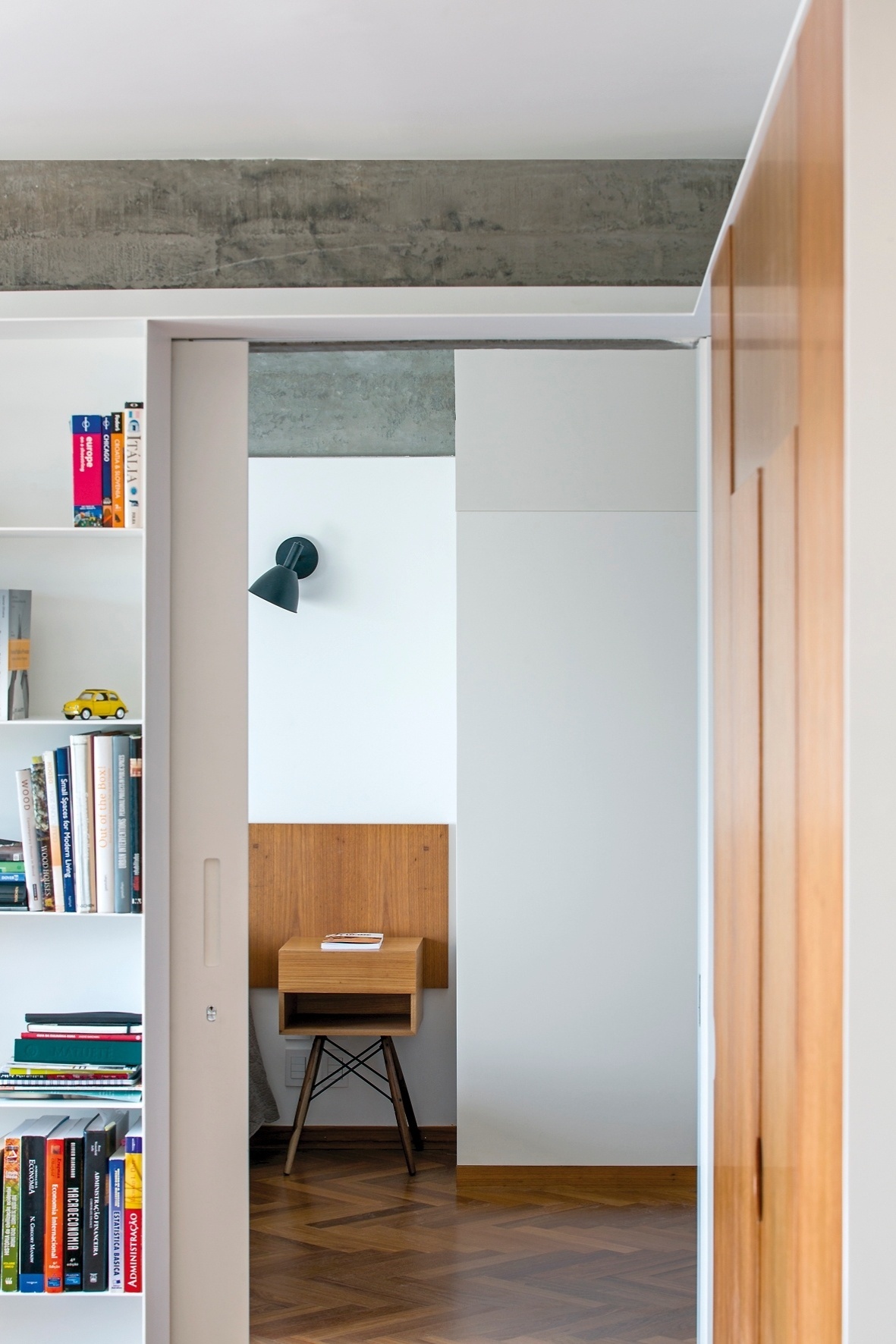 Uma chapa de aço-carbono (DIX Arte&Metal) avança sobre a porta do dormitório, contornando a parede à direita. Ali, a mesma serralheria vira caixa-estrutura para abrigar a marcenaria. Os projetistas do escritório Pascali Semerdjian criaram o armário para esconder o ar-condicionado que refrigera o Apartamento FT, em São Paulo - Leonardo Finotti/ UOL