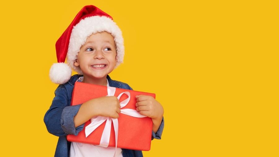 Menino com gorro de papai noel e presente