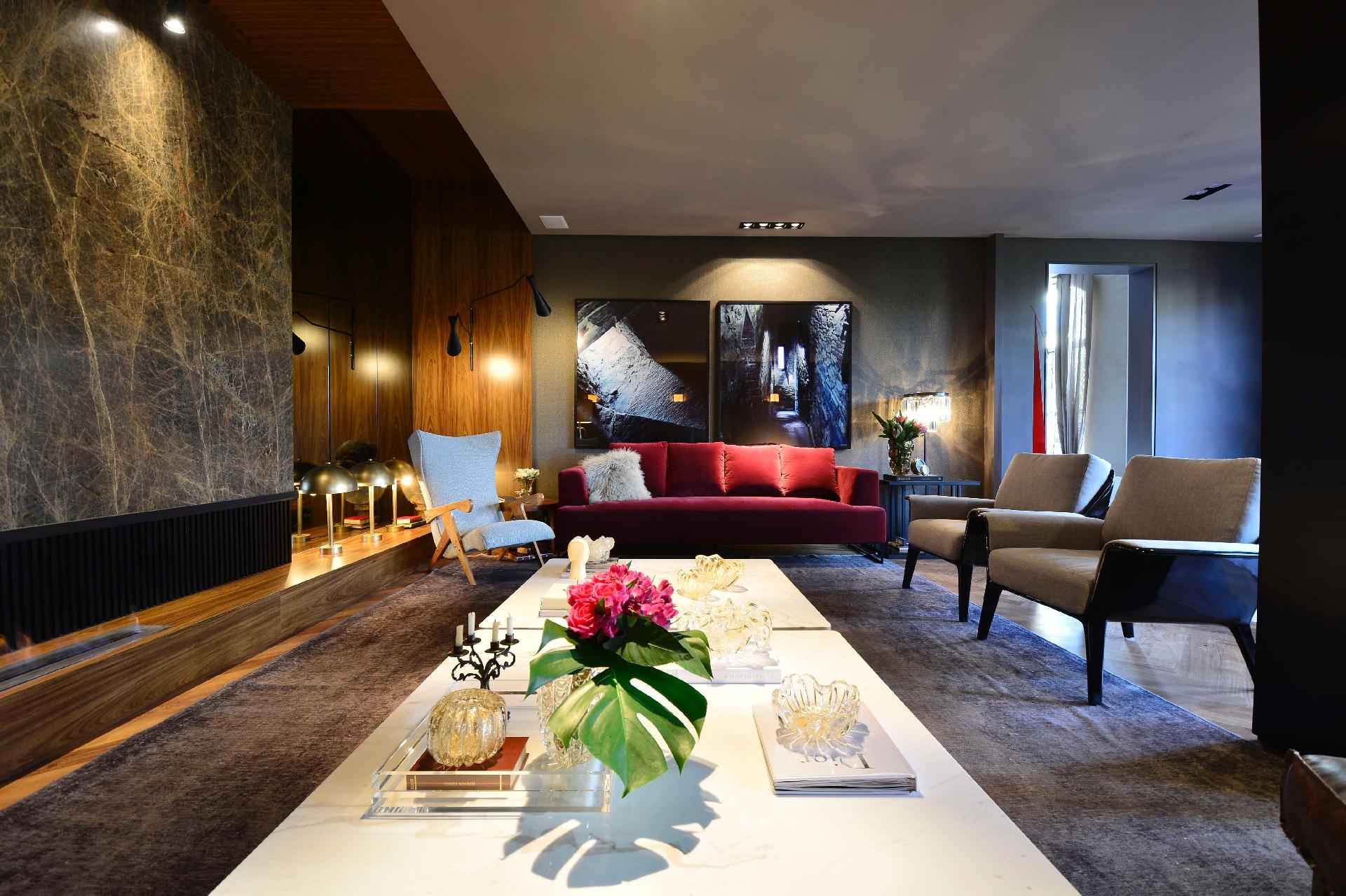 Os arquitetos Ana Hnszel e Marcelo Polido assinam a sala 'Ar' Deco, inspitada no estilo Art Déco. A madeira é a aposta da dupla, vista nos painéis melanínicos que lembram ipê, destacados pela iluminação cênica do espaço. O piso é de tacões de cumaru e as amplas mesas de mármore dividem espaço com o sofá aveludado na cor vinho - Eduardo Liotti/ Divulgação