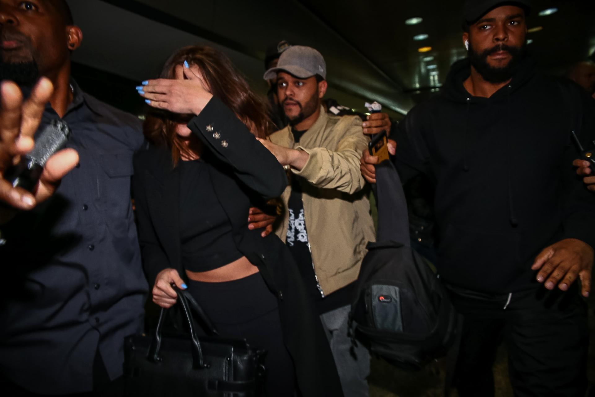 Em meio a tumulto, Selena Gomez e The Weeknd desembarcam no aeroporto de Guarulhos, em São Paulo sob forte escolta de seguranças - Raphael Castello/AgNews
