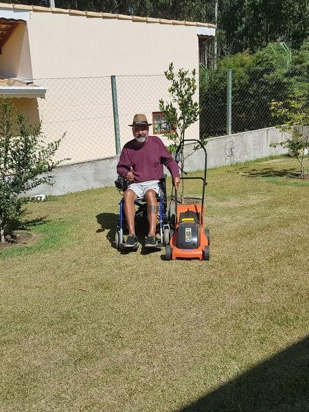 Edison Ferreira operando seu cortador de grama adaptado, em sua propriedade.