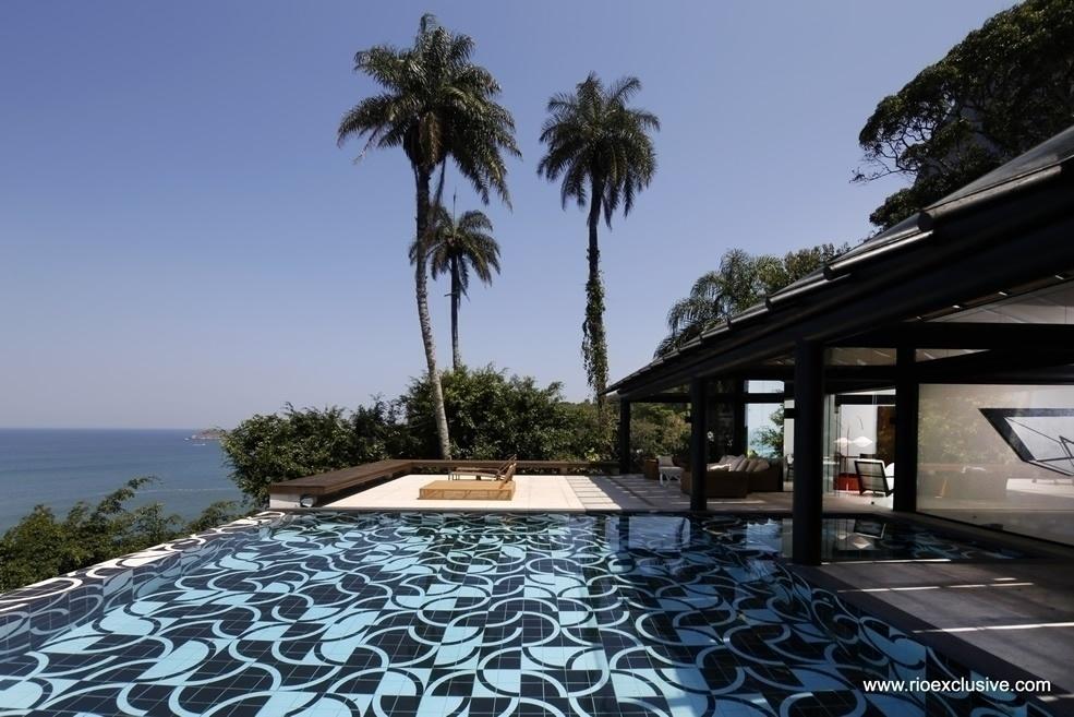 A piscina tem borda infinita e azulejos preto e branco, além de vista para a Pedra da Gávea - Reprodução/ Rio Exclusive