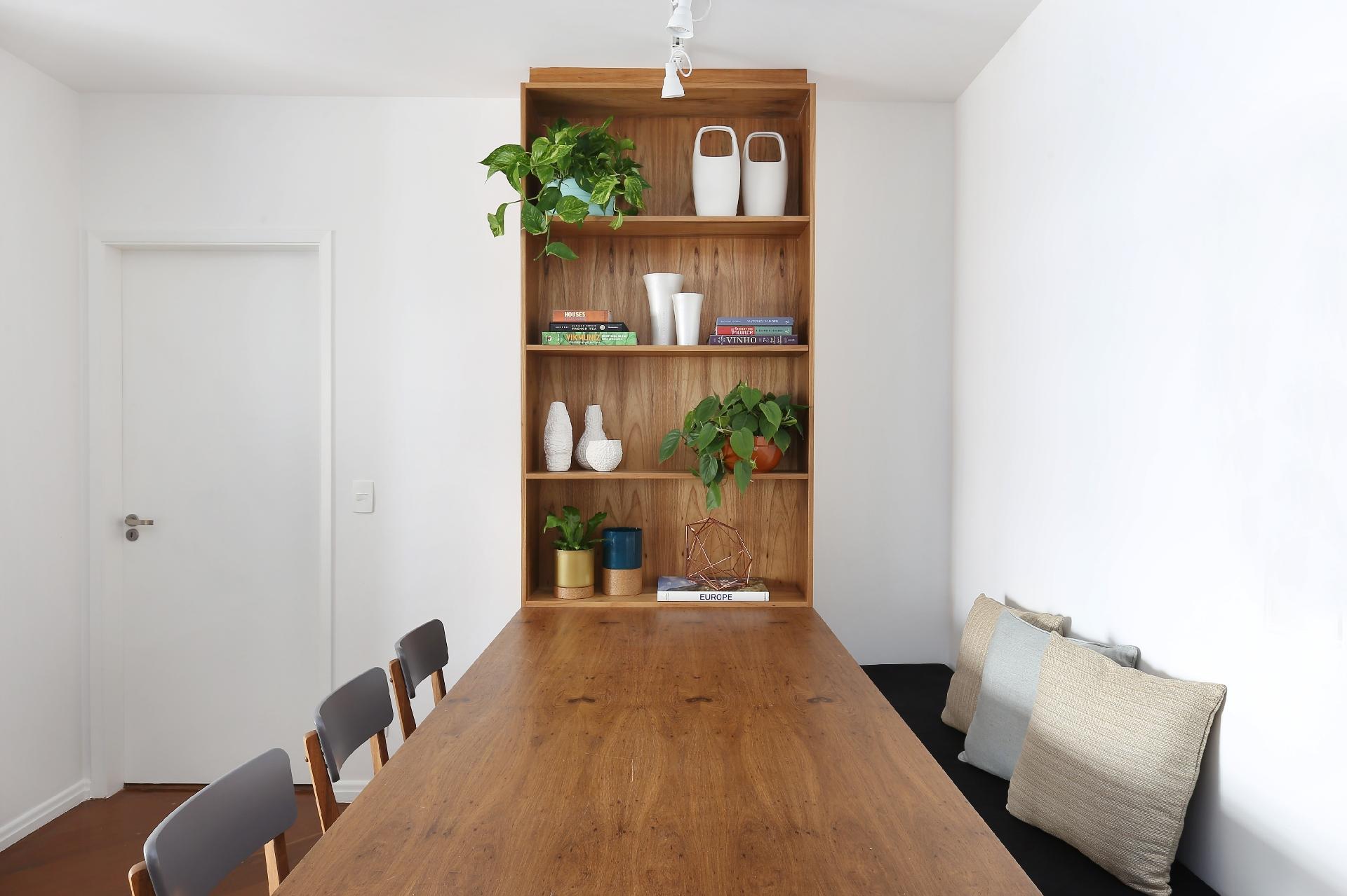 A ideia do escritório ACF Arquitetura era criar uma área de convívio despojada, cheia de vida e ?sem frescura?. A aposta foi por um banco do lado da parede com almofadas para apoiar as costas. Na extremidade da mesa, a mesma marcenaria do tampo se transforma em uma estante, onde objetos decorativos e plantas criam uma decoração permanente para o local - Mariana Orsi/Divulgação