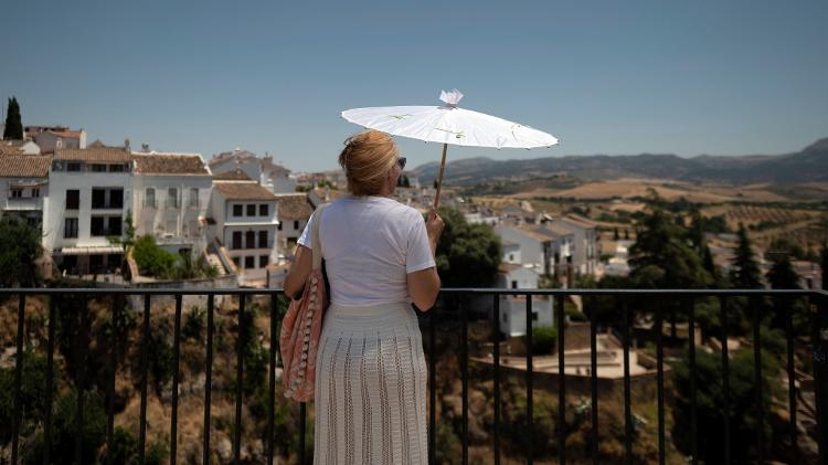 Mulher usa um sombrinha para se proteger do sol enquanto observa a paisagem em Ronda, no sul da Espanha Mulher usa um sombrinha para se proteger do sol enquanto observa a paisagem em Ronda, no sul da Espanha