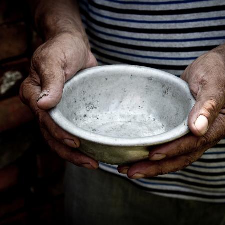 Homem com fome segura prato de comida vazio - Getty Images/iStockphoto