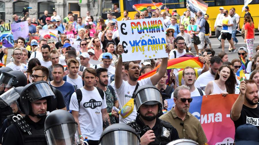 Homem segura cartaz com as frases "existe uma família, existe a Ucrânia" durante Parada do Orgulho LGBTQ+ em Kiev - Genya SAVILOV/AFP
