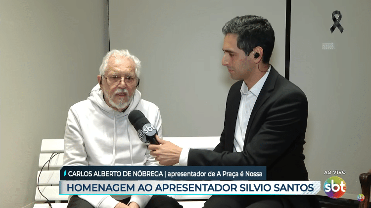 Carlos Alberto Nóbrega concedeu entrevista sobre Silvio Santos sentado em primeiro banco usado no cenário de 'A Praça É Nossa' (SBT)