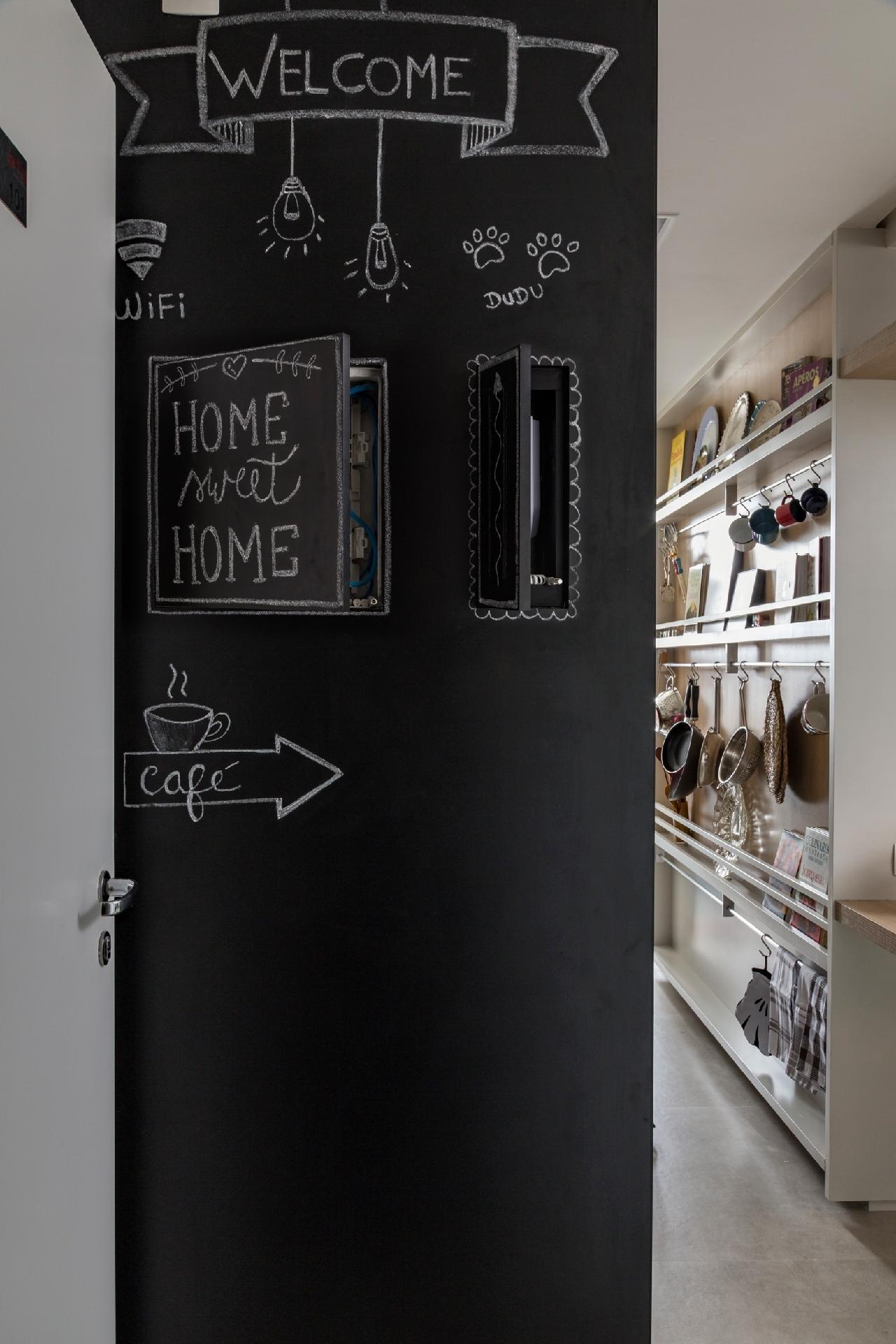Para disfarçar o quadro de luz e o interfone, posicionados na entrada do apartamento, as arquitetas da doob arquitetura bolaram um divertido painel forrado de laminado preto tipo lousa, onde os moradores gostam de escrever com giz. Executado pela Marcenaria Sasdelli, ele contém duas portinhas (33 x 33 cm e 33 x 16 cm) que funcionam com fecho toque, dispensando puxadores - Evelyn Müller | Divulgação