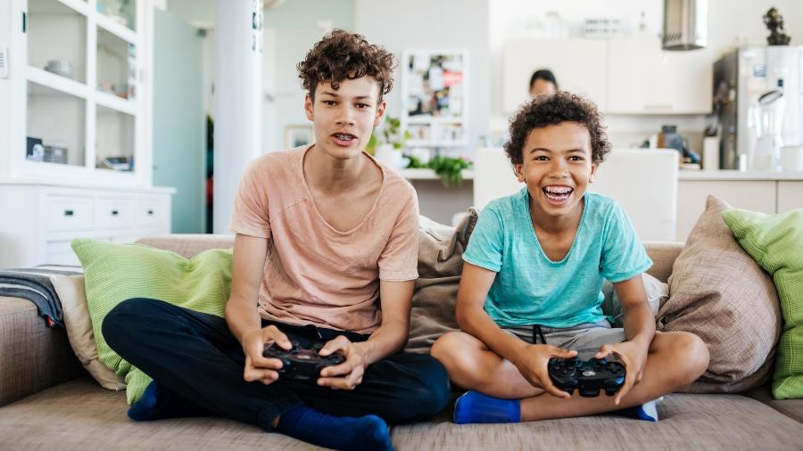 Garotos jogam videogame na sala de casa - Getty Images