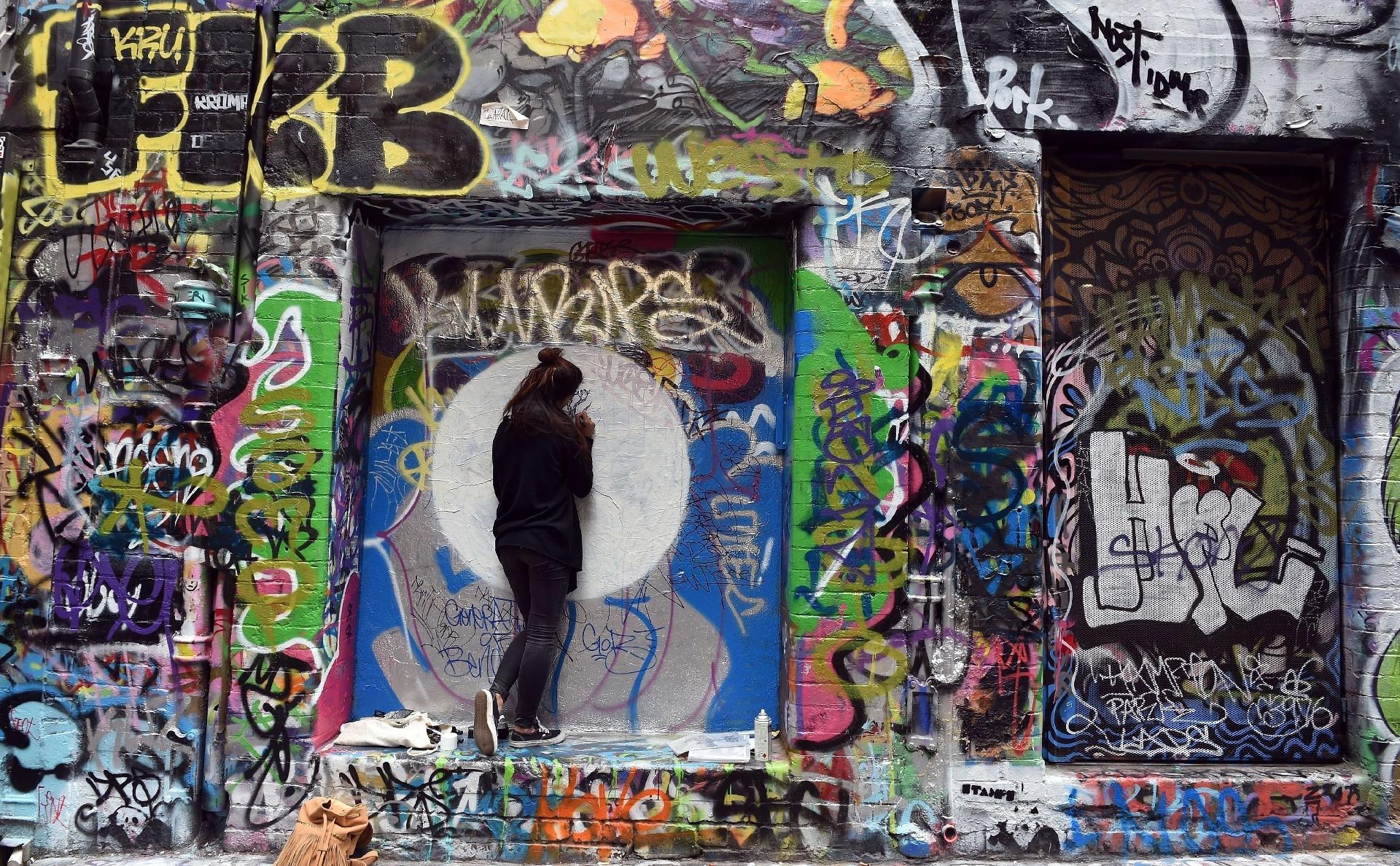 Artista retoca obra em Melbourne, na Austrália - INDRANIL MUKHERJEE/AFP