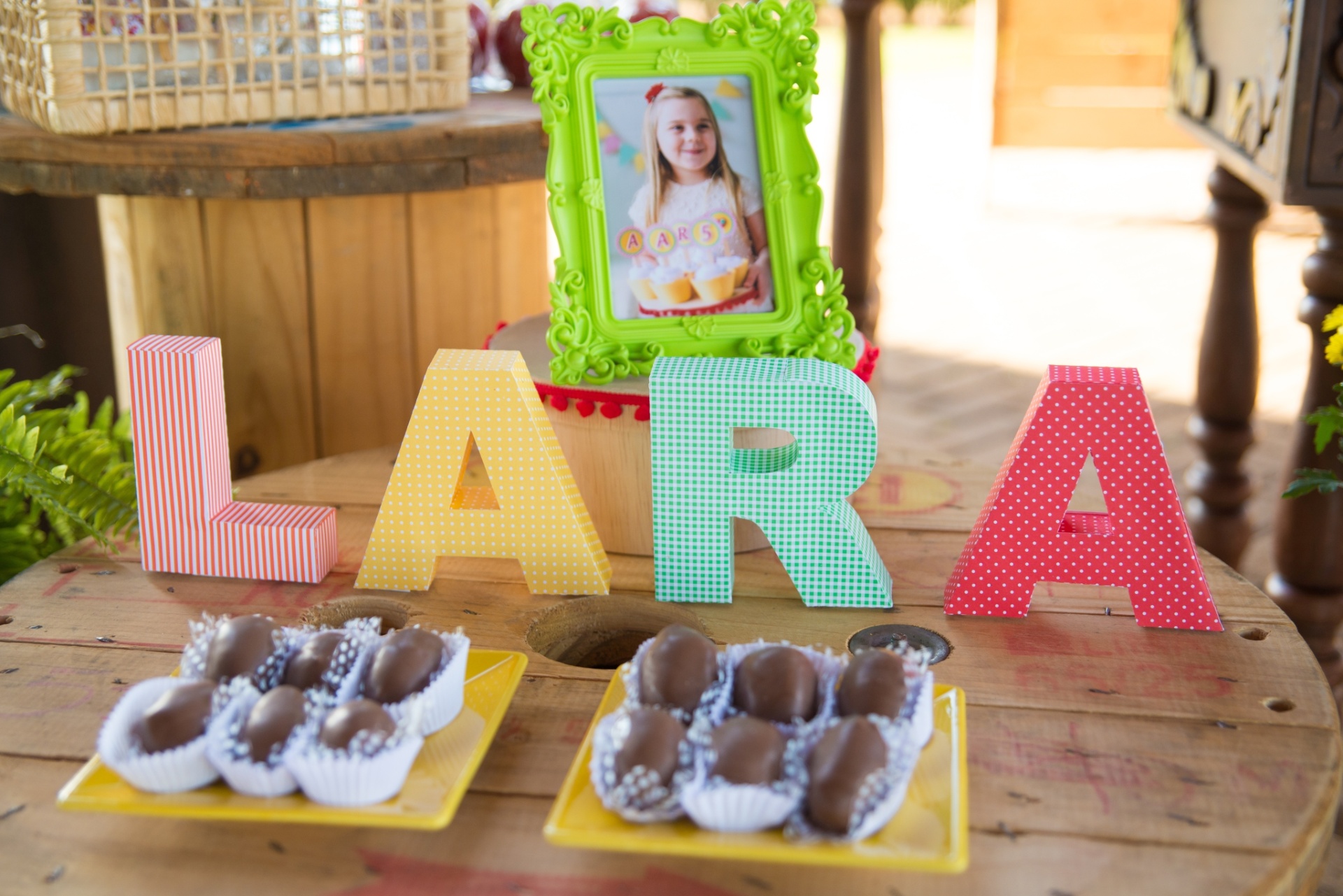 Carretéis de madeira reaproveitados de lojas que vendem materiais elétricos serviram de apoio para os bombons de morango, da Doce Gulla (www.facebook.com/Doce-Gulla-Londrina-1447644815532615). O nome da aniversariante foi confeccionado em papel especialmente para a festa - Karl Ellwein/Dueto em Versos/Divulgação