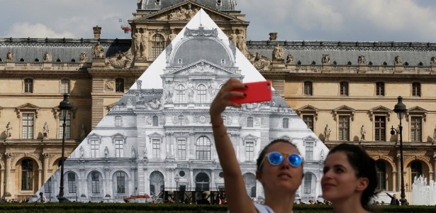 Jovens tiram selfie com instalação do fotógrafo JR ao fundo, em Paris - Pascal Rossigno/Reuters - Pascal Rossigno/Reuters