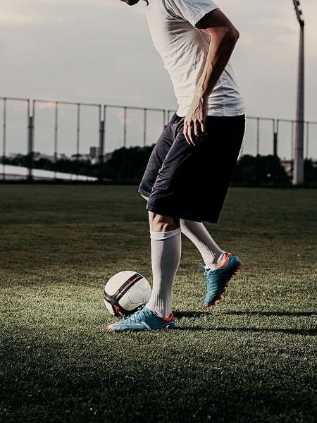 Esporte, treinamento de futebol e pessoas - jogador de futebol jogando com  bola no campo