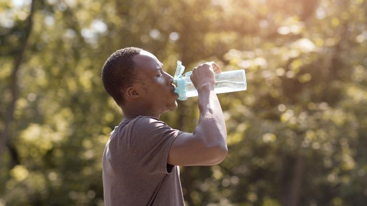 Homem jovem bebe água, hidratação, bebendo água, líquido, calor, verão, suor - iStock - iStock