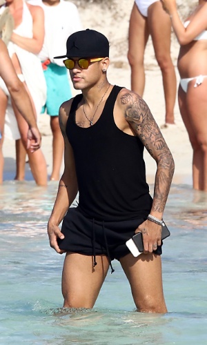 28.jul.2015 - De férias, Neymar entra no mar em praia de Ibiza, na Espanha, e enrola os shorts para não molhar a roupa
