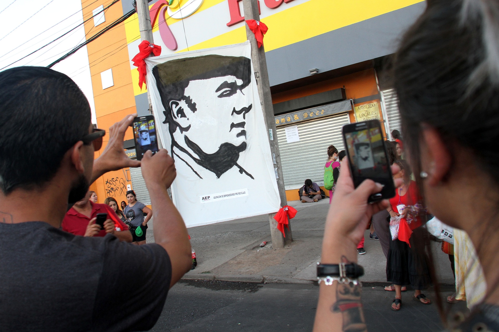 26.dez.2015 - Casal fotografa painel nas ruas de Santiago que retrata Pablo Neruda durante o espetáculo "Neruda vem voado" - EFE/ELVIS GONZÁLEZ