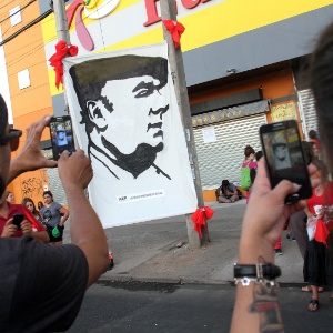 26.dez.2015 - Casal fotografa painel nas ruas de Santiago que retrata Pablo Neruda durante o espetáculo "Neruda vem voado" - EFE/ELVIS GONZÁLEZ
