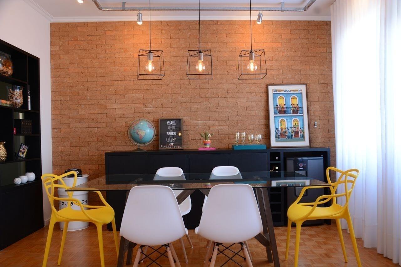 Nathalia Bilibio buscou referência do estilo industrial para criar este ambiente. Perfilados metálicos foram utilizados para as luminárias direcionáveis e os pendentes. Já os tijolinhos marcam presença na parede do bufê, que também abriga um bar com adega. Na lateral, uma antiga porta de entrada para o corredor se transformou em uma estante vazada, onde objetos decorativos ganham destaque - Carlos Edler/Divulgação