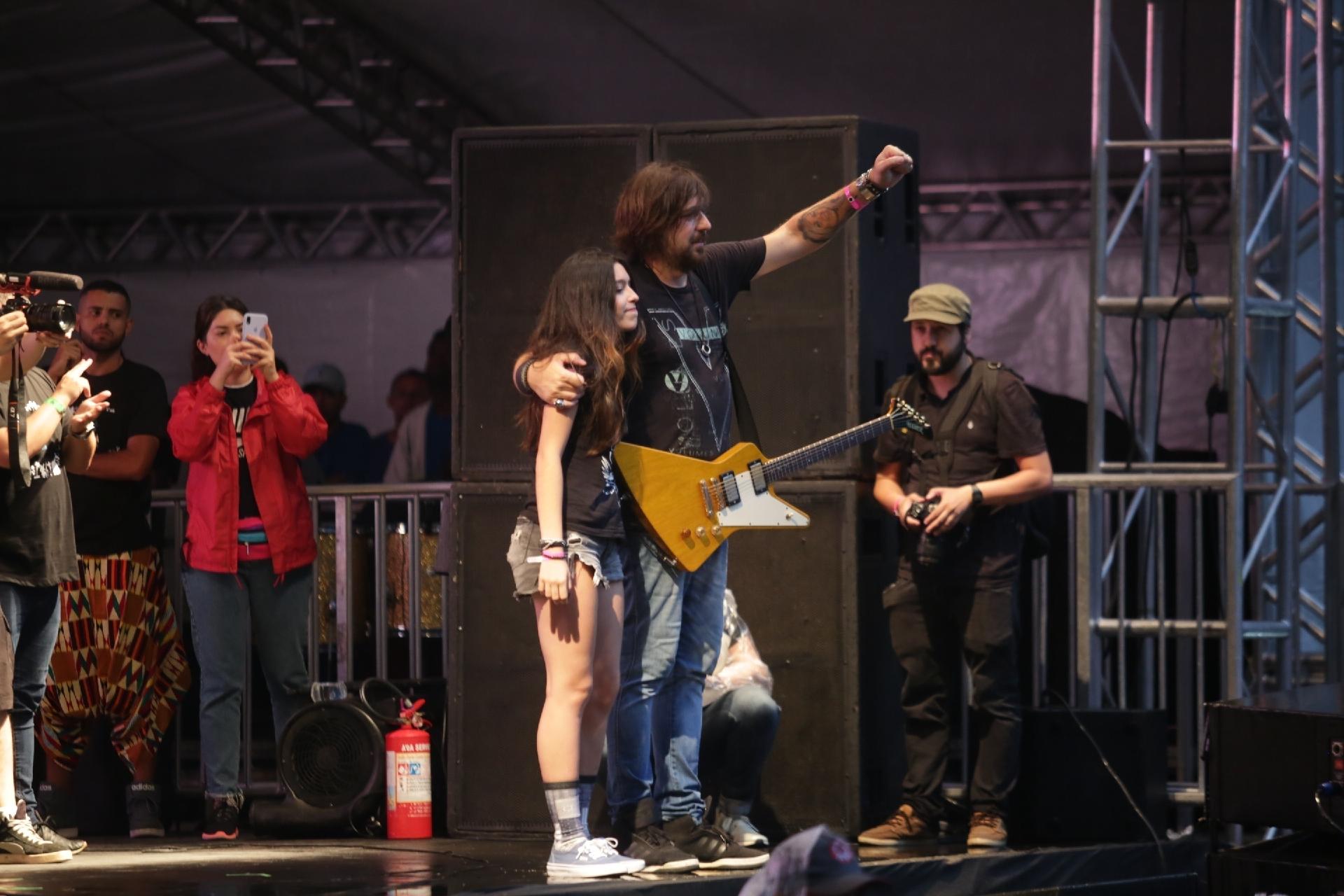 O guitarrista Marcão recebe Luíza, uma das filhas de Champignon, no palco da festa do aniversário de São Paulo - Diego Padgurschi/UOL