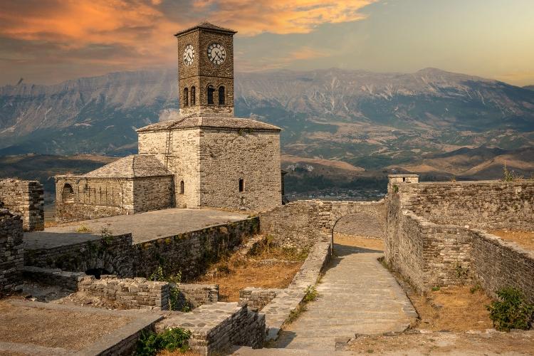 Pôr do sol sobre torre do relógio e fortaleza no castelo de Gjirokaster, na Albânia