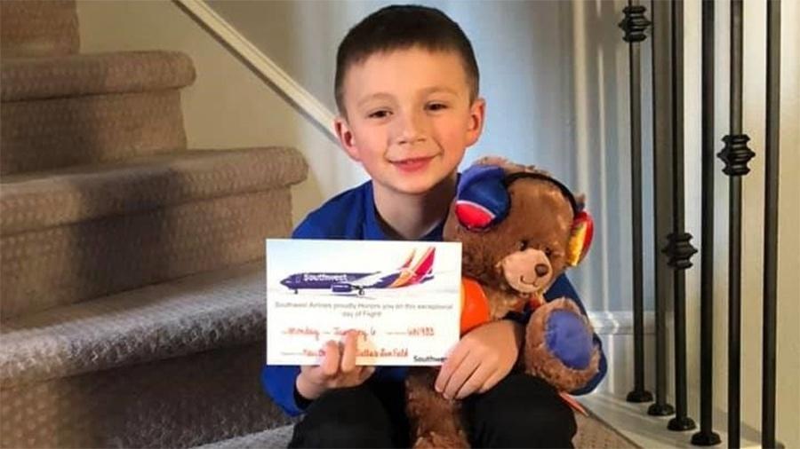 Grayson com seu novo ursinho de pelúcia dado pela Southwest Airlines - Reprodução