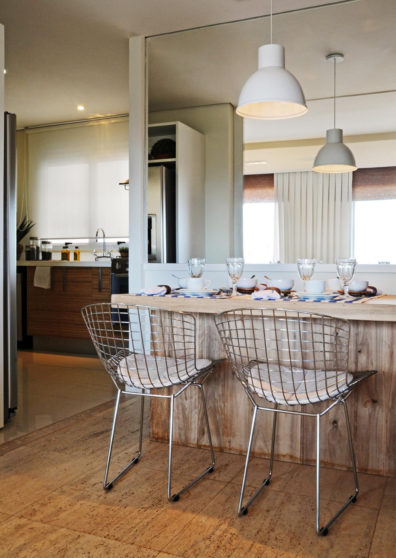 Pequenas mesas de madeira que servem duas pessoas podem ser encostadas a paredes espelhadas, para evitar a sensação de confinamento, como neste projeto da arquiteta Débora Aguiar. As cadeiras metálicas Bertoia de linhas delicadas, quase transparentes, ajudam a compor um ambiente mais limpo e amplo - Carlos Piratininga/ Divulgação