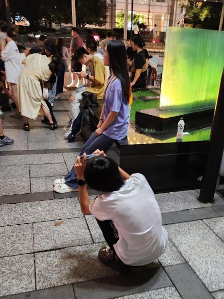 Homem em Xangai para na posição "asian squat" para tirar foto de mulher