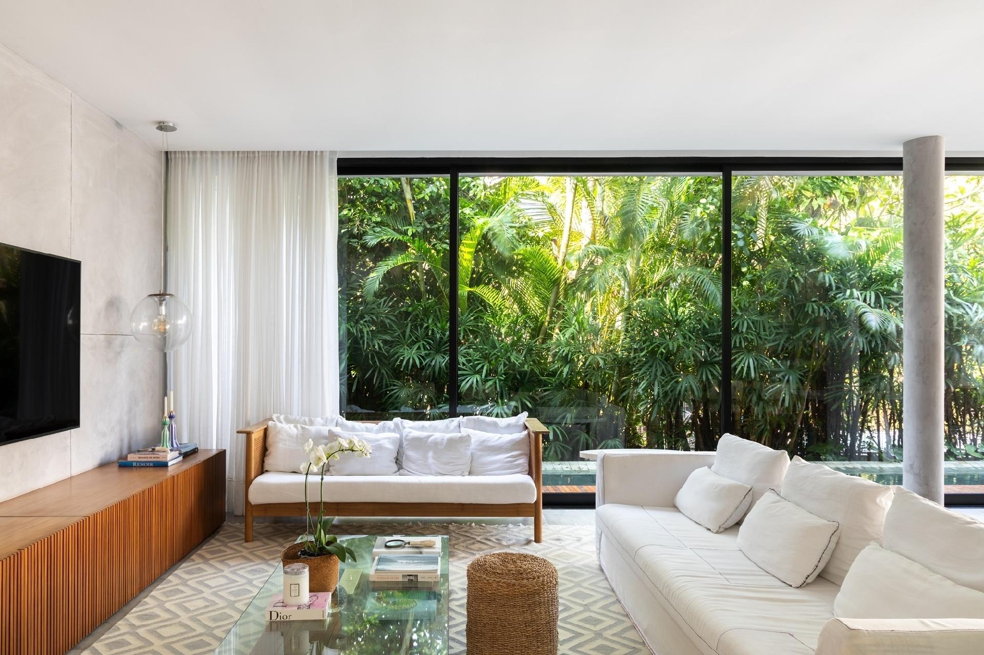 Na decoração, o sofá principal de capa branca, a mesa de centro e a mesa de jantar branca vieram do apartamento antigo. Na seleção dos móveis novos, os arquitetos partiram dessas peças aproveitadas, da arquitetura contemporânea da casa e da integração entre a área interna e externa. - Luiza Schreier/Divulgação