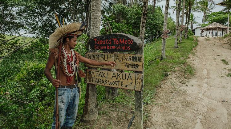 Tohõ Pataxó, professor de patxohã, o idioma Pataxó, mostra as placas instaladas na entrada da aldeia: o projeto também pretende desenvolver etnoturismo e ser um centro de preservação cultural, aprendizado e troca de saberes entre povos indígenas Tohõ Pataxó, professor de patxohã, o idioma Pataxó, mostra as placas instaladas na entrada da aldeia: o projeto também pretende desenvolver etnoturismo e ser um centro de preservação cultural, aprendizado e troca de saberes entre povos indígenas