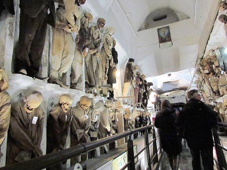 Turistas caminham entre restos mortais expostos nas Catacumbas dos Capuchinhos
